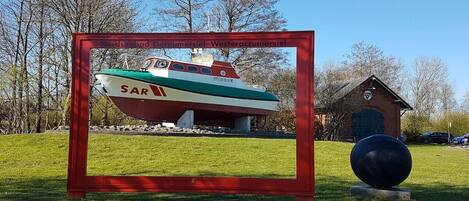 Um modelo de barco emoldurado com o texto 'Nordsøbad Dornumersiel - Westeraccummsiel' e um pequeno edifício com um relógio.