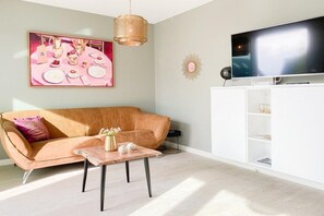 Ein Wohnzimmer mit einer Couch, einem Couchtisch, einem Fernseher und einem Schrank.