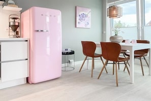 Eine moderne Küche mit einem pinkfarbenen Kühlschrank, Holzstühlen und einem Esstisch.