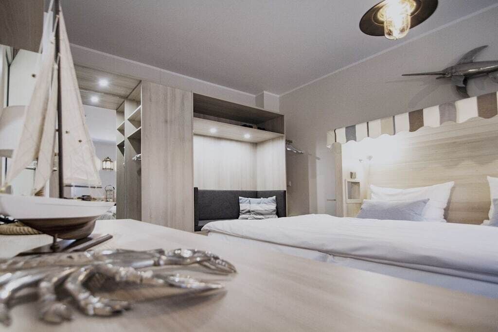 Et hotelværelse med seng, sengebord og vægmonteret hylde.
