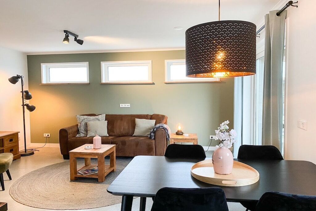 Ein Wohnzimmer mit Sofa, Couchtisch, Esstisch und Pendelleuchte.
