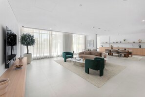 A modern living room with a sofa, chairs, a coffee table, and a television. - StayShort - Refined Classy 1 Bedroom in Dubai Hills - Sleeps 4! (Dubai Hills)