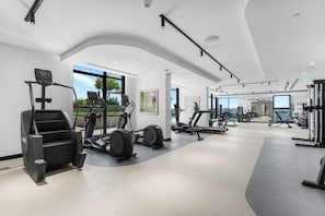 A modern gym with various exercise equipment, large windows, and a clean, spacious layout. - StayShort - Refined Classy 1 Bedroom in Dubai Hills - Sleeps 4! (Dubai Hills)