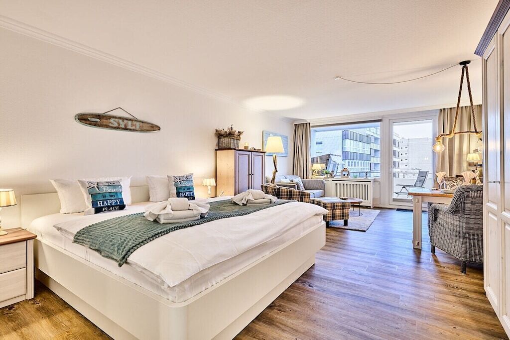 Habitación de hotel con una cama grande, un escritorio, una silla y vistas a la ciudad a través de la ventana.