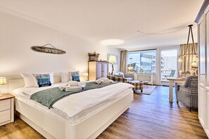 Habitación de hotel con una cama grande, un escritorio, una silla y vistas a la ciudad a través de la ventana.