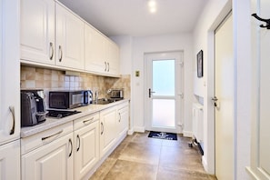 A kitchen with white cabinets, a microwave, a coffee maker, and a toaster. There is a door leading to another room. - Apartment in Westerland with swimming pool (Westerland)
