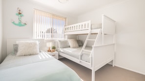 Ein Schlafraum mit Etagenbett, Fenster, Lampe und Anker als Wanddekoration.