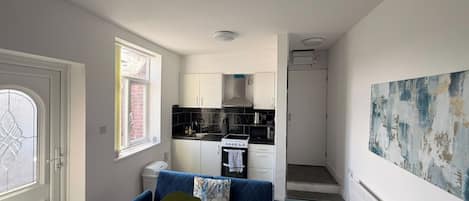 A compact living space with a kitchenette, a blue sofa, and a radiator.