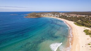 A coastal landscape with a clear beach, a small island, and a town in the background. - Sunset Shores 1 Surf Air , 24 Marine Dr - air con , Wi-Fi, across to the beach (Fingal Bay)