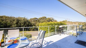 A balcony with a table set for dining, a grill, and a view of the surrounding landscape. - Sunset Shores 1 Surf Air , 24 Marine Dr - air con , Wi-Fi, across to the beach (Fingal Bay)