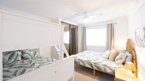 A bedroom with a bunk bed, a single bed, a ceiling fan, and a window with curtains. - Sunset Shores 1 Surf Air , 24 Marine Dr - air con , Wi-Fi, across to the beach (Fingal Bay)
