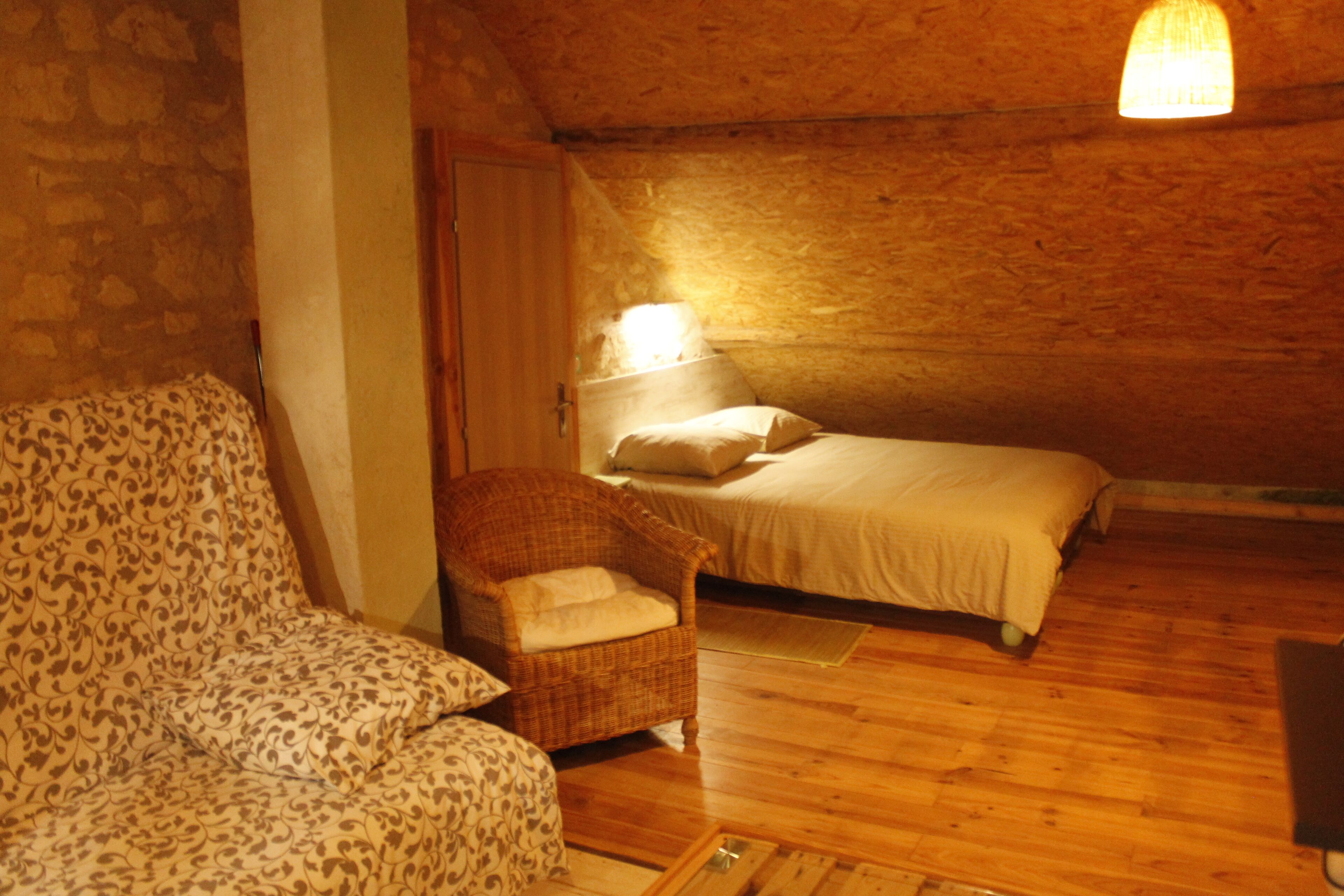 Une pièce confortable avec un lit, une chaise et une lampe.