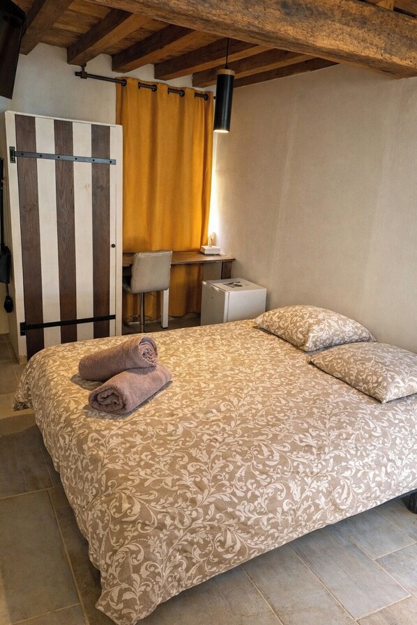 A bedroom with a bed, a desk, and a chair.