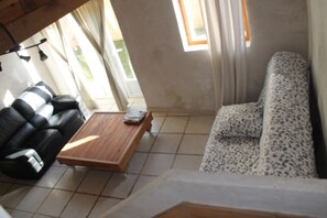 A living room with a sofa, a coffee table, and a window with curtains. - 3-bedroom vacation rental for 10 people with on-site Caribbean catering (Bellechaume)