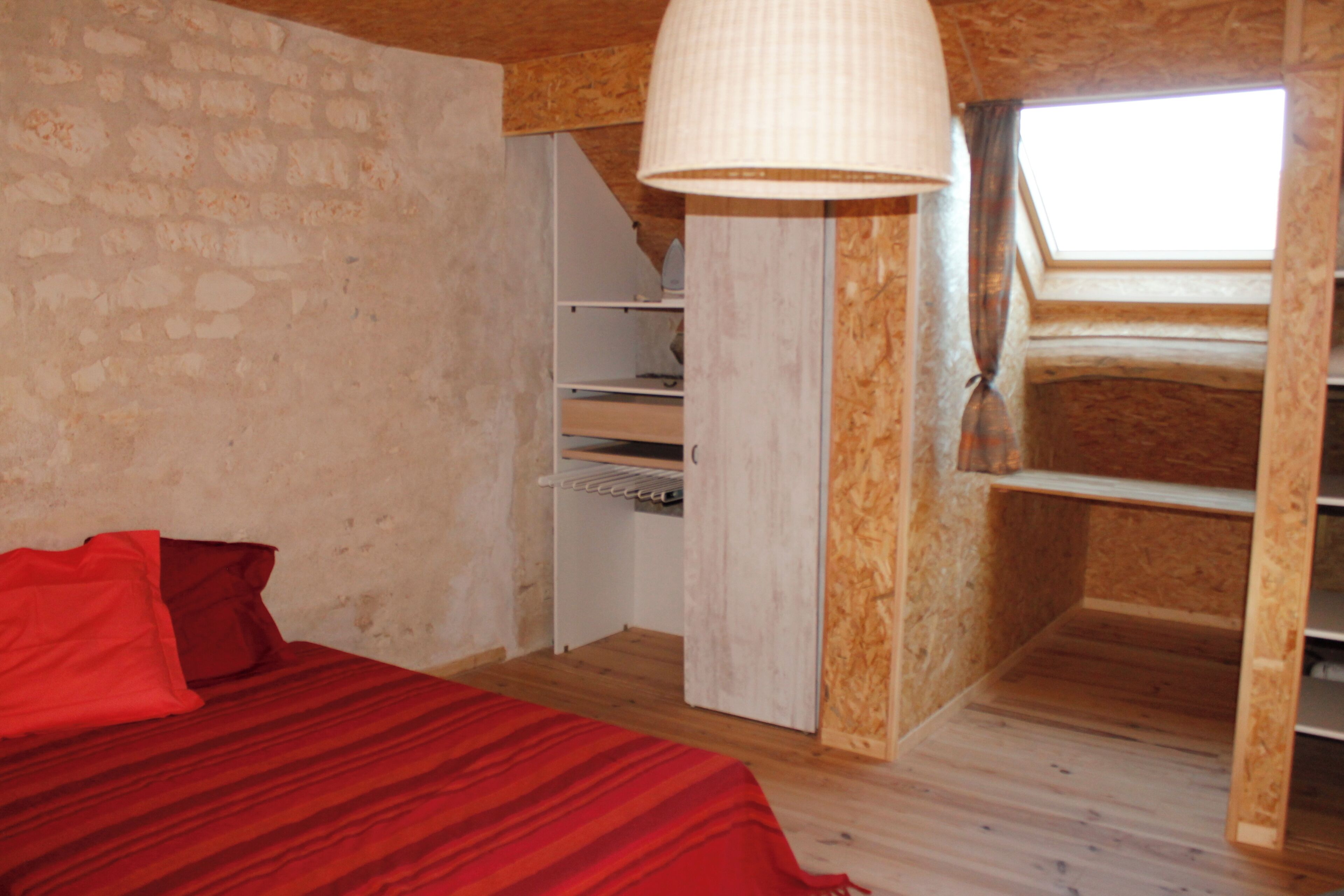 A bedroom with a bed, a wardrobe, and a skylight.