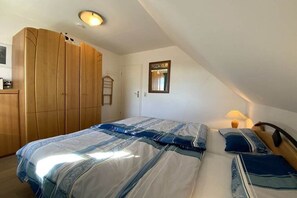 A bedroom with a large bed, a wardrobe, a mirror, and a ceiling light. - Morning sun in Bültenhus (Born\/Darß)