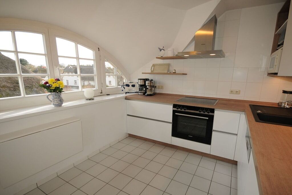 A kitchen with white cabinets, a stove, and a coffee maker.