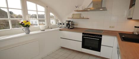 A kitchen with white cabinets, a stove, and a coffee maker.