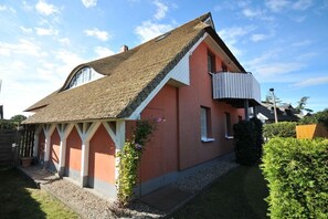 Ein Haus mit geneigtem Dach, einem Balkon und einem Garten.