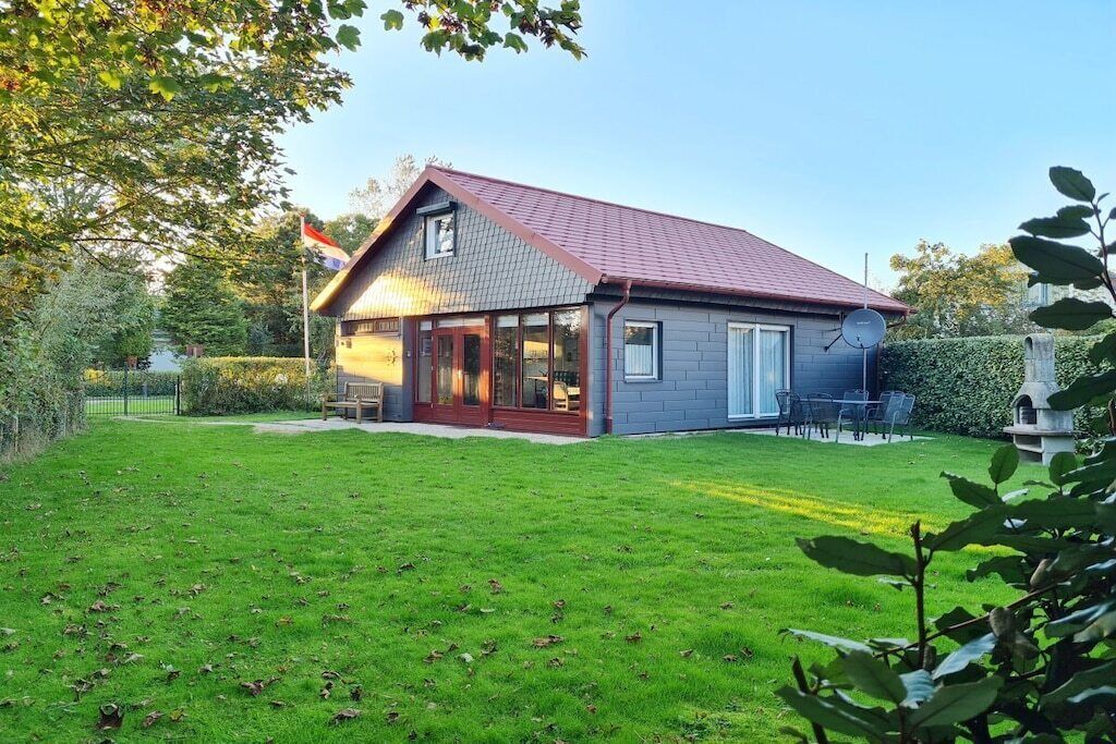 Une maison avec un toit rouge, une antenne parabolique et une pelouse bien entretenue.