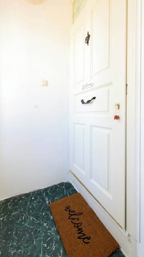 Een witte deur met een 'Welcome' welkomstmat en een klein decoratief object erboven.