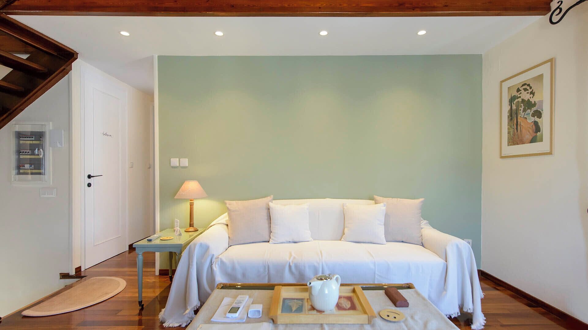 A bedroom with a bed, bedside table, lamp, and a framed picture on the wall.