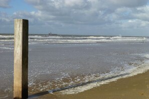 Un poste de madera en la playa con olas acercándose.