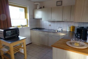 A compact kitchen with a microwave, sink, and stove. - Holiday home with 3 bedrooms (PD Julianadorp)