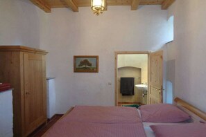 A bedroom with two beds, a wooden wardrobe, a painting, and a bathroom visible through an open door. - Manor house at the moated castle (Vierkirchen)