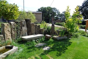 A garden with stone structures, a small pond, and a pathway.