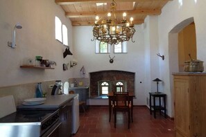 A kitchen with a fireplace, wooden ceiling, and a chandelier. - Manor house at the moated castle (Vierkirchen)