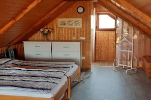 Un dormitorio acogedor en el ático, con cama, cómoda y una ventana pequeña.