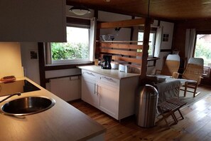 A compact kitchen with a sink, a coffee maker, and a small dining area with a chair. - at Lake Selent in Pülsen (Pülsen)