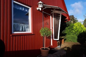 Un edificio rojo con ventana, puerta y una planta en maceta.