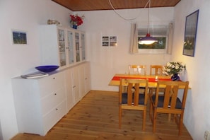 A compact kitchen with a dining table, chairs, and a cabinet with glass doors. - at Lake Selent in Pülsen (Pülsen)
