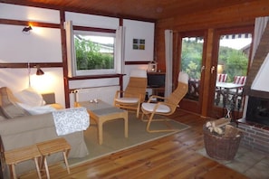 A cozy room with a sofa, chairs, a small table, a fireplace, and a view of greenery outside. - at Lake Selent in Pülsen (Pülsen)