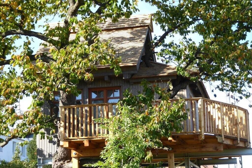 A wooden house with a balcony, surrounded by trees.