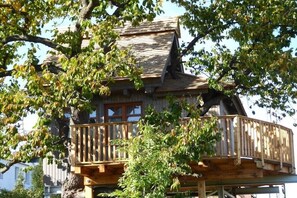 Una casa di legno con un balcone, immersa tra gli alberi.