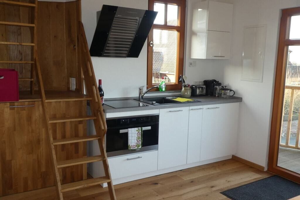 A compact kitchen with a built-in oven, a dishwasher, and a window with a view.
