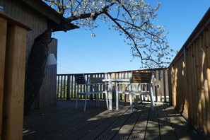 Una terrazza esterna con ringhiere in legno, un tavolo e delle sedie.