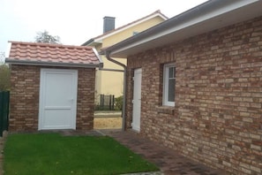 A brick house with a white door and a small attached garage. - Villa Belair Schmidt (Wurster Nordseeküste Ortsteil Dorum-Neufeld)