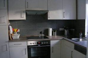 A modern kitchen with a stove, oven, and sink. - Villa Belair Schmidt (Wurster Nordseeküste Ortsteil Dorum-Neufeld)