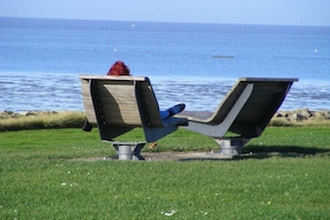Un banc sur lequel est assis une personne, donnant sur une étendue d’eau.