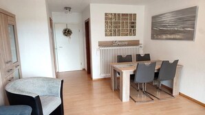 Un coin repas comprenant une table et des chaises, un radiateur et un mur orné d’un tableau encadré.