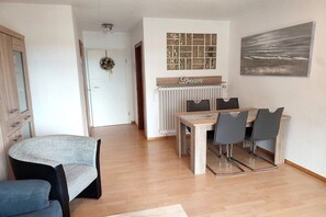Un coin repas comprenant une table et des chaises, un radiateur et un mur orné d’un tableau encadré.
