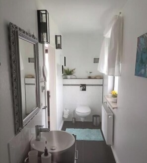 Een kleine badkamer met een wastafel, toilet en spiegel.