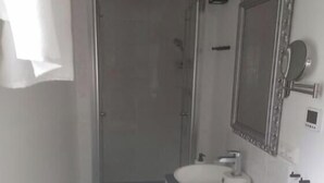 Un bagno con un lavandino bianco, uno specchio e una doccia.