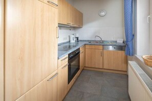 A compact kitchen with wooden cabinets, a built-in oven, and a sink. - Holiday apartment in Juist with swimming pool (Juist)