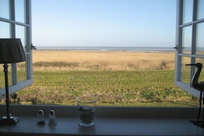 A window with a view of a beach and grassy fields. - "Dream view" in the Sölring-Hüs (Sylt\/OT Rantum)