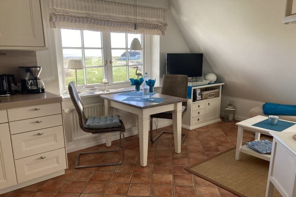 A compact kitchen with a dining area, a television, and a view of the outdoors.